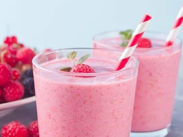 Rosa Abnehmshake mit Himbeeren in zwei Gläsern mit Strohhalm