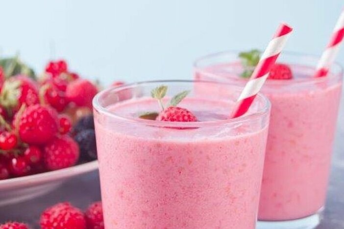 Rosa Abnehmshake mit Himbeeren in zwei Gläsern mit Strohhalm
