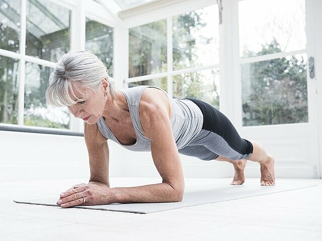 Protein-Shakes-sportliche-Frau-macht-Liegestütz-auf-Matte