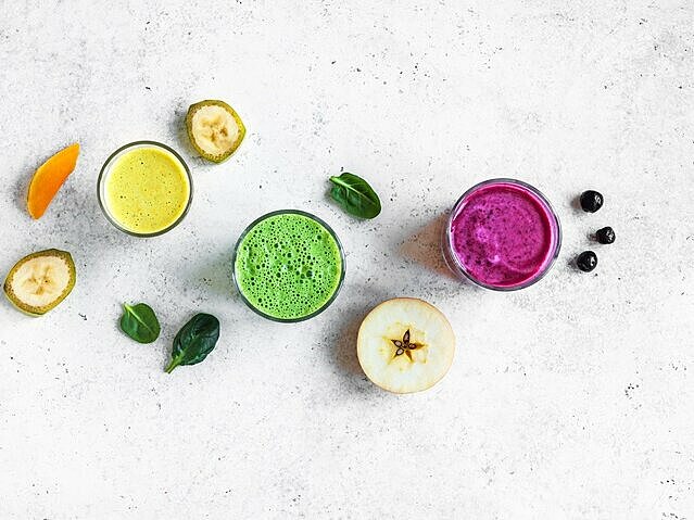 3 bunte Smoothies im Glas mit gesunden Zutaten drumherum