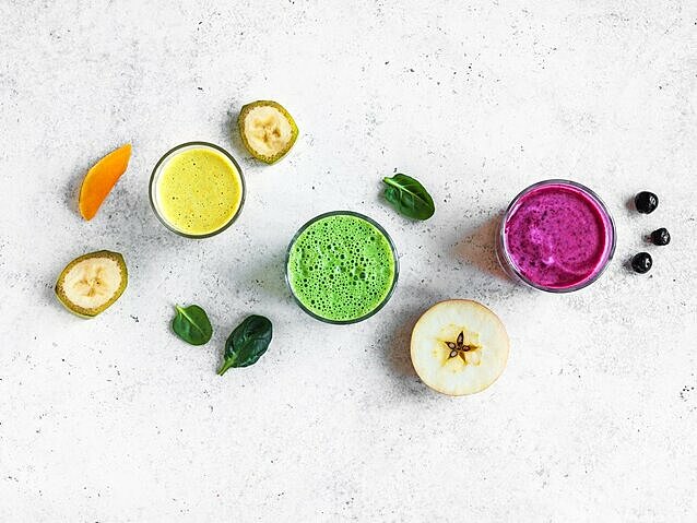 3 bunte Smoothies im Glas mit gesunden Zutaten drumherum